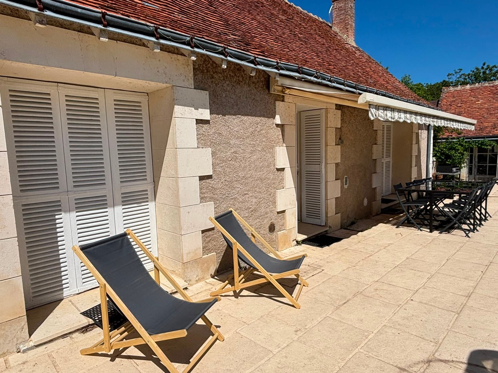 Terrasse ensoleillée avec transats et table extérieure devant le gîte Marie-France